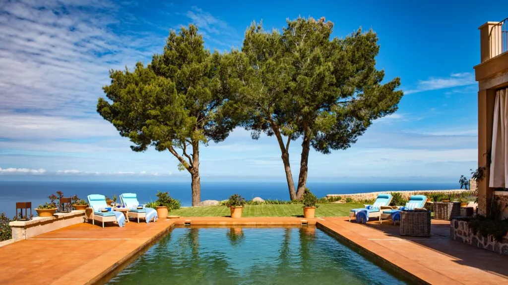 Luxury Villa and sunbeds with pool and two large scot pine trees looking over the sea. Photograph taken in France, Miquelet
