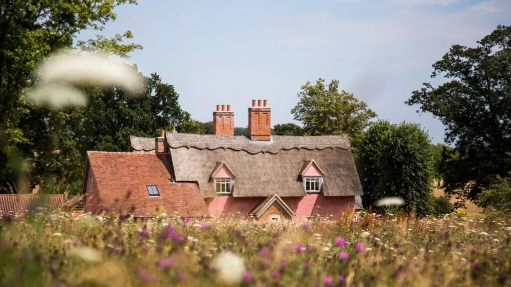 Luxury cottage nestled in the english countryside, with wild flower meadow in the foreground. Photograph taken in a villa in England, Suffolk
