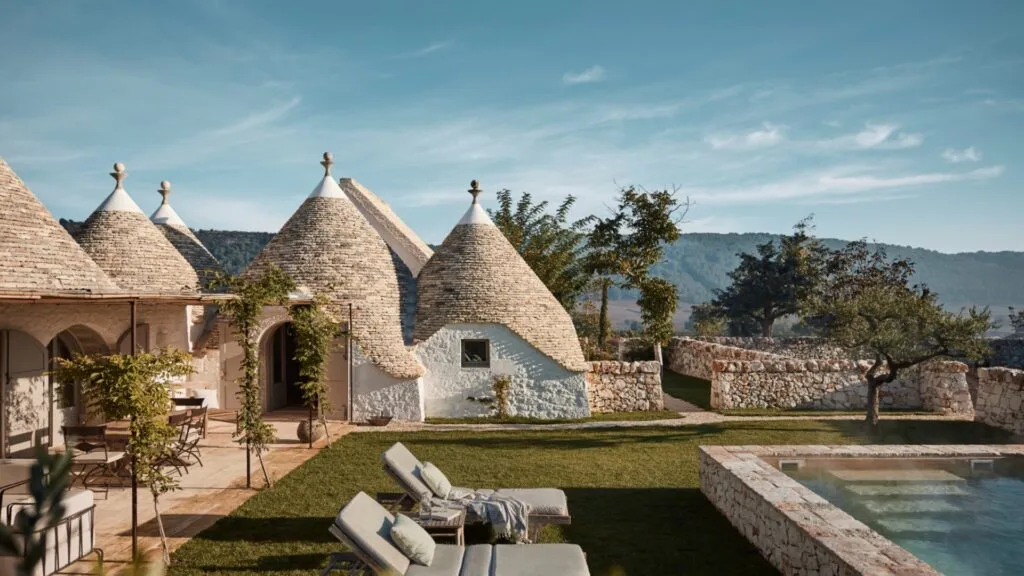 A group of traditional houses of Pulia; characteristically, they feature pyramidal, domed or conical roofs built up of corbelled limestone slabs. with large surrounding garden and pool. Photograph taken in a villa in Italy, Pulia